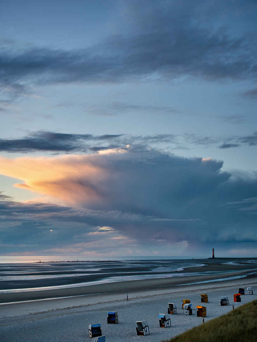 Ruhige Nordseeküste bei Sylt mit Wattenmeer, Strandkörben und dramatischem Abendhimmel